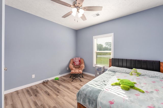 bedroom featuring visible vents, baseboards, a textured ceiling, and wood finished floors