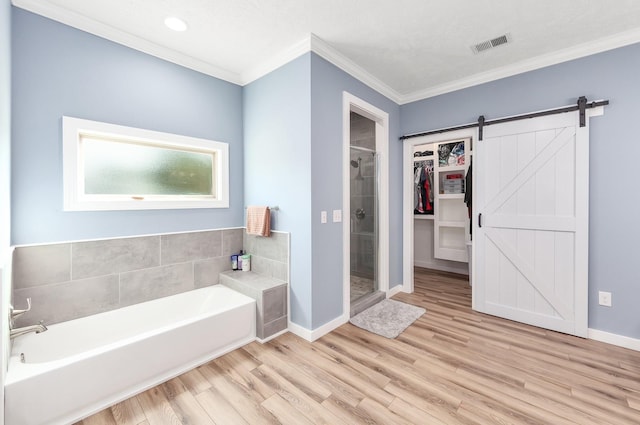 bathroom with visible vents, a garden tub, ornamental molding, wood finished floors, and a shower stall