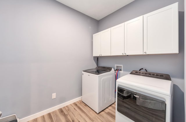 clothes washing area with baseboards, cabinet space, independent washer and dryer, and light wood finished floors