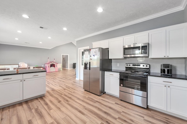 kitchen featuring stainless steel appliances, dark countertops, visible vents, and light wood finished floors