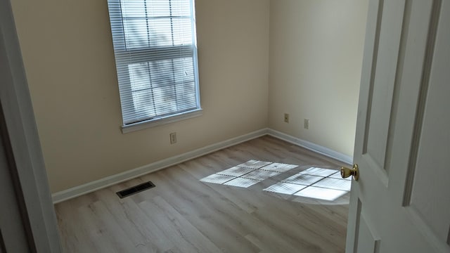 spare room featuring wood finished floors, baseboards, and visible vents