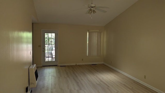 empty room featuring light wood-type flooring, ceiling fan, heating unit, and vaulted ceiling