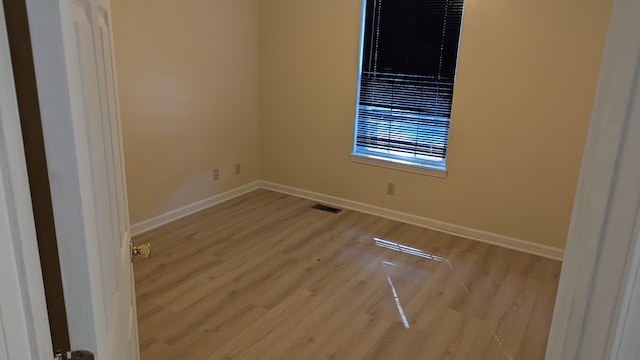 empty room featuring wood finished floors, visible vents, and baseboards