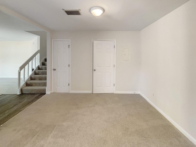 empty room with stairway, visible vents, baseboards, and carpet