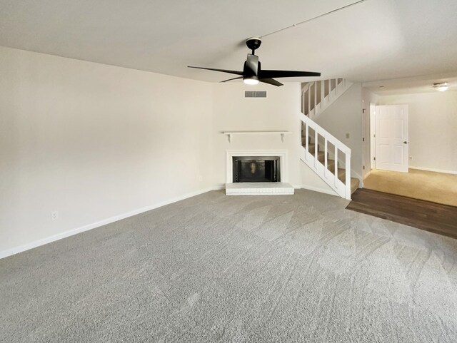 unfurnished living room with carpet flooring, ceiling fan, and a brick fireplace