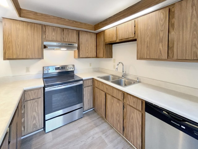 kitchen with light wood-style flooring, a sink, light countertops, appliances with stainless steel finishes, and under cabinet range hood