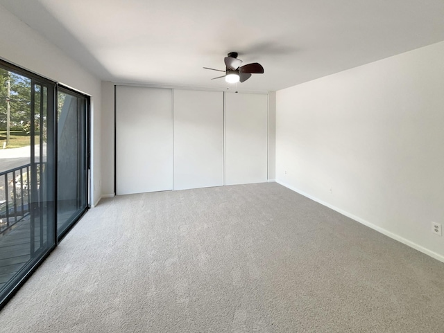 carpeted empty room with baseboards and a ceiling fan