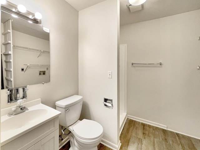 bathroom with vanity, wood finished floors, baseboards, a stall shower, and toilet