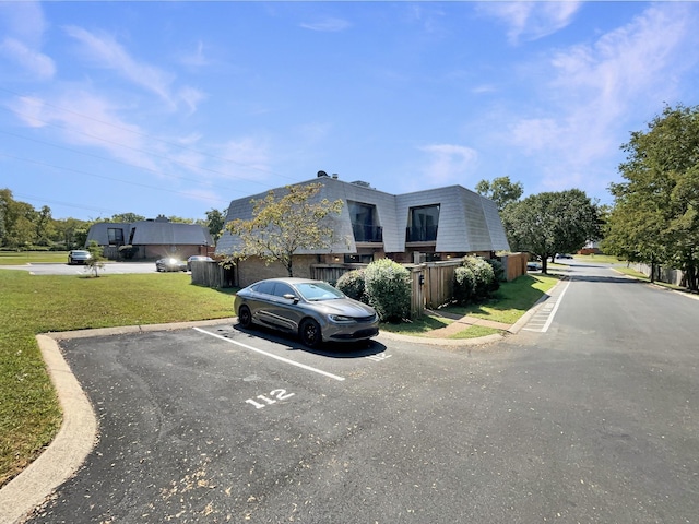 exterior space with uncovered parking and a front lawn