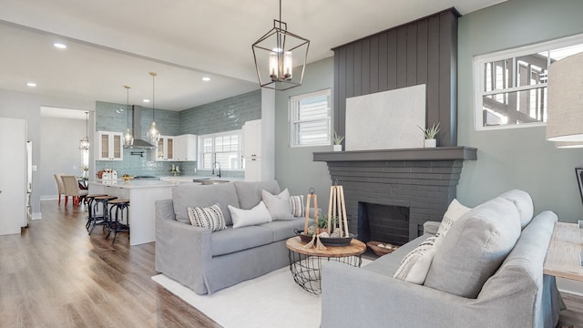 living room with sink, a notable chandelier, hardwood / wood-style floors, and a fireplace