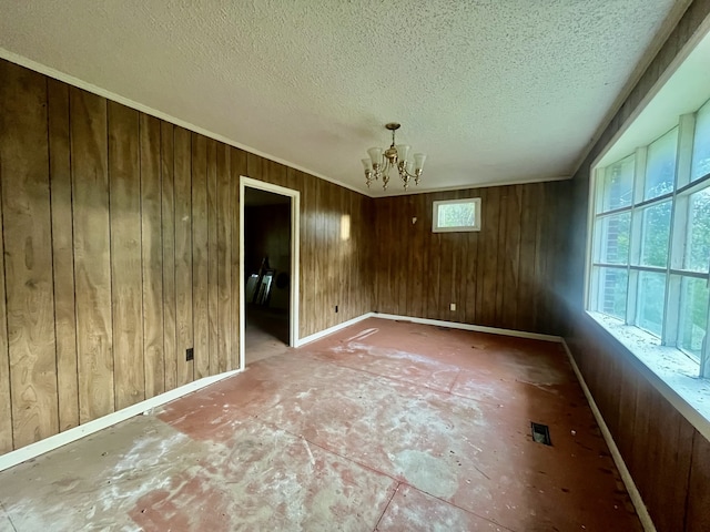 unfurnished room featuring a textured ceiling, wooden walls, and a chandelier