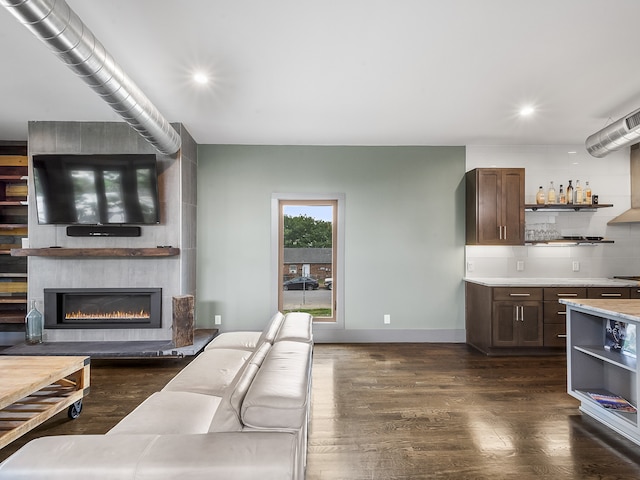 living room with a fireplace, dark wood-type flooring, and bar area