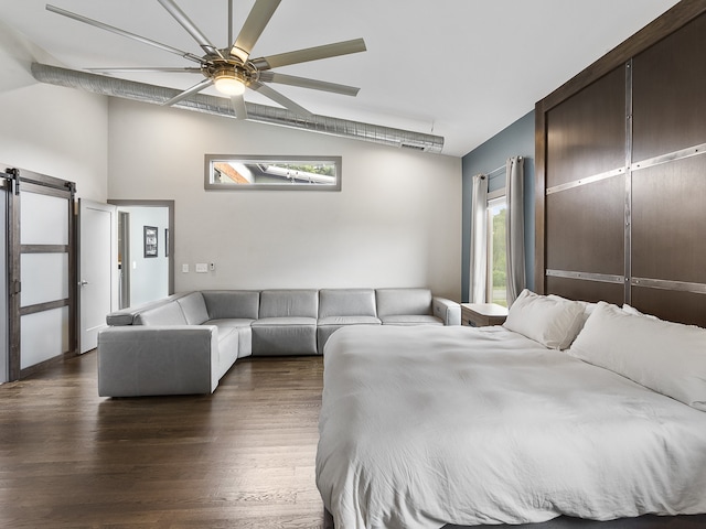 bedroom with a barn door, ceiling fan, and dark hardwood / wood-style flooring