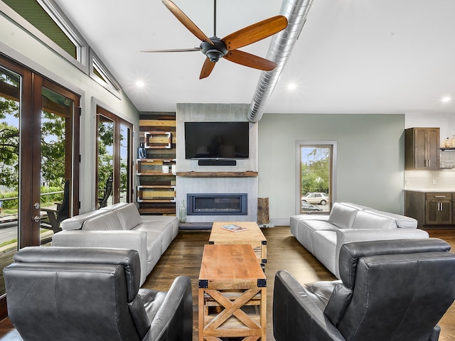 living room with a large fireplace, ceiling fan, and dark wood-type flooring