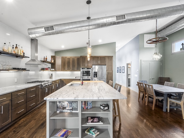 kitchen with an island with sink, wall chimney range hood, appliances with stainless steel finishes, and light stone countertops