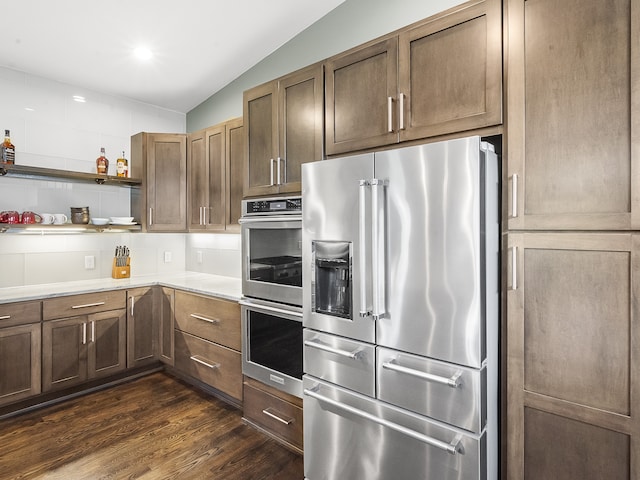 kitchen featuring backsplash, appliances with stainless steel finishes, dark hardwood / wood-style floors, and vaulted ceiling