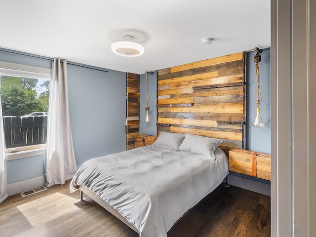 bedroom with hardwood / wood-style flooring and wooden walls