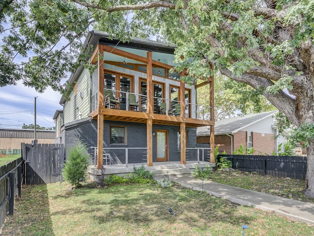 rear view of house featuring a balcony and a yard