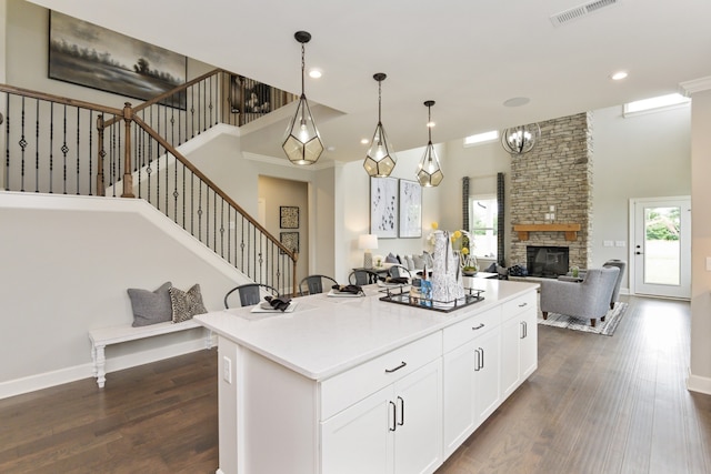 kitchen with a center island, decorative light fixtures, white cabinetry, dark hardwood / wood-style flooring, and a fireplace