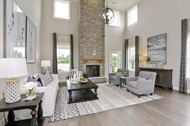 living room with a high ceiling, hardwood / wood-style flooring, a stone fireplace, and a healthy amount of sunlight