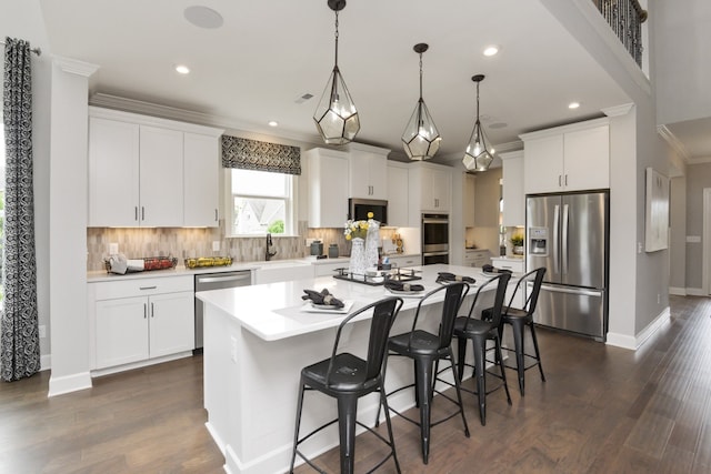 kitchen with pendant lighting, white cabinetry, a kitchen bar, a center island, and stainless steel appliances