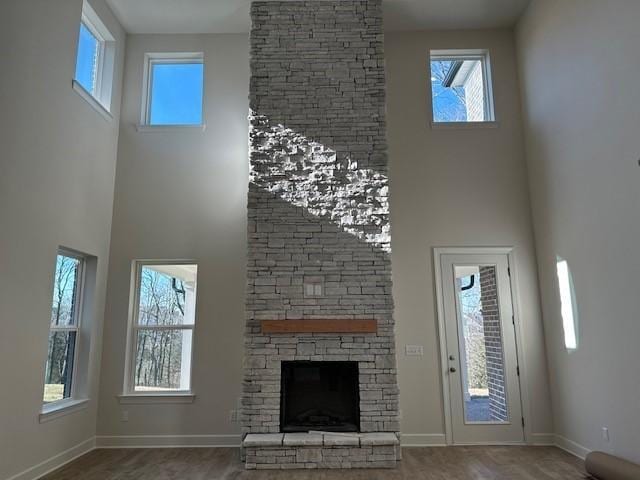 unfurnished living room with a towering ceiling and a stone fireplace