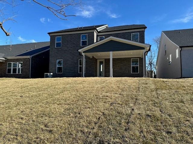 back of property with a yard and central AC