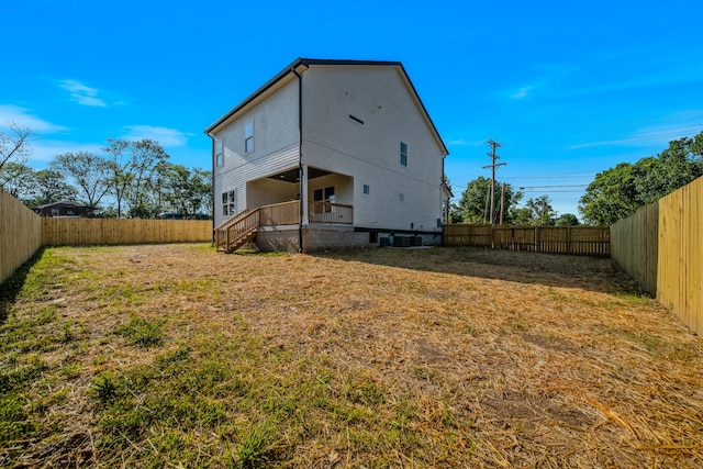 back of house featuring central AC unit and a lawn