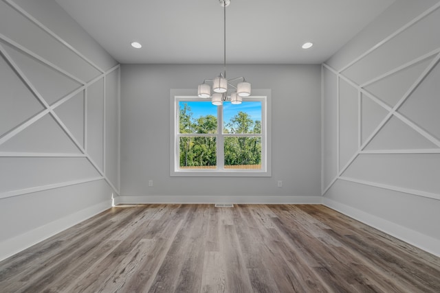 unfurnished dining area featuring vaulted ceiling, a notable chandelier, and hardwood / wood-style floors