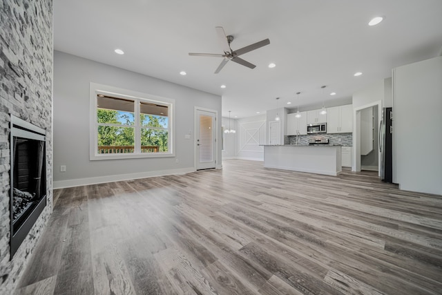 unfurnished living room featuring a fireplace, ceiling fan, and light hardwood / wood-style floors