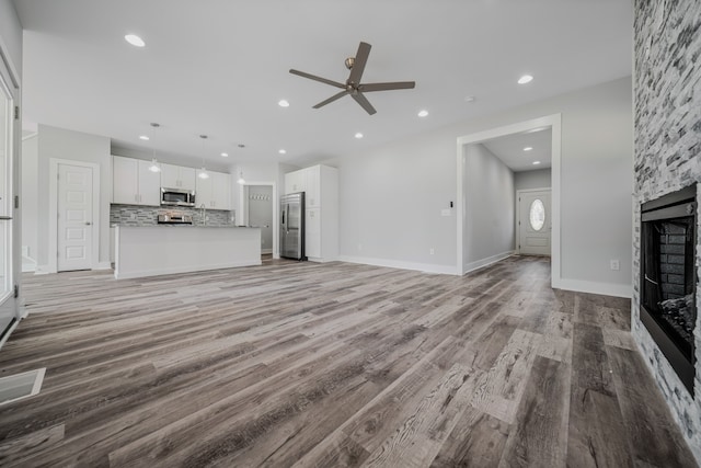 unfurnished living room with ceiling fan, hardwood / wood-style floors, and a fireplace