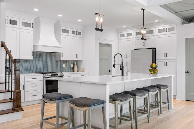 kitchen featuring custom range hood, stainless steel appliances, sink, and an island with sink