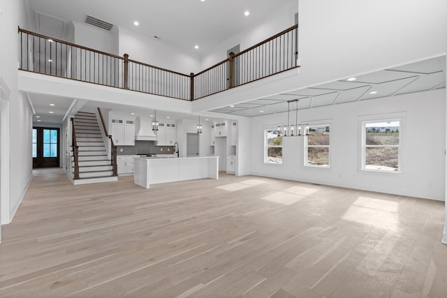 unfurnished living room featuring a high ceiling and light hardwood / wood-style flooring