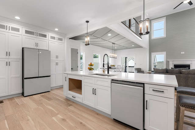 kitchen with white cabinetry, stainless steel appliances, decorative light fixtures, and sink