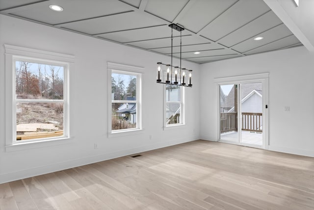 unfurnished dining area featuring a wealth of natural light, a chandelier, and light hardwood / wood-style floors