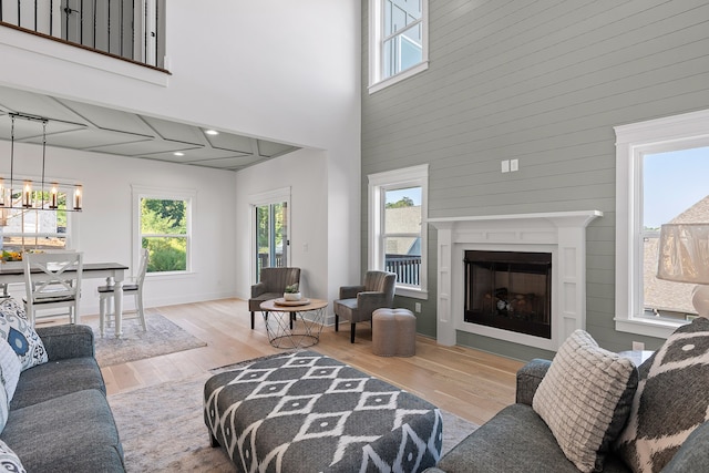 living room featuring an inviting chandelier, light hardwood / wood-style flooring, and a high ceiling