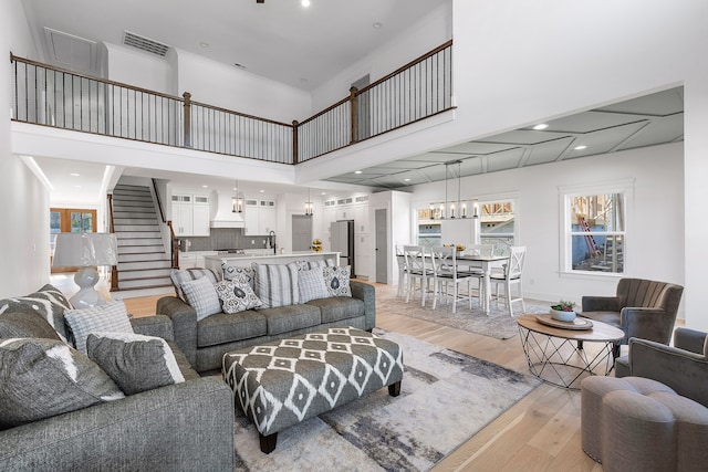 living room featuring light hardwood / wood-style floors, sink, and a towering ceiling