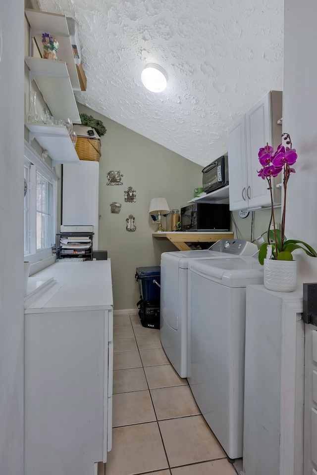 washroom with cabinets, light tile patterned floors, a textured ceiling, and washing machine and dryer