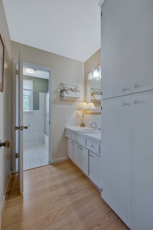 bathroom featuring vanity, hardwood / wood-style floors, decorative backsplash, and walk in shower