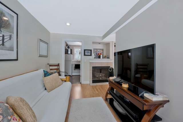 living room featuring a tiled fireplace and light wood-type flooring