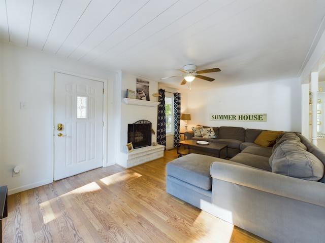 living room featuring light wood-type flooring, a fireplace, and ceiling fan