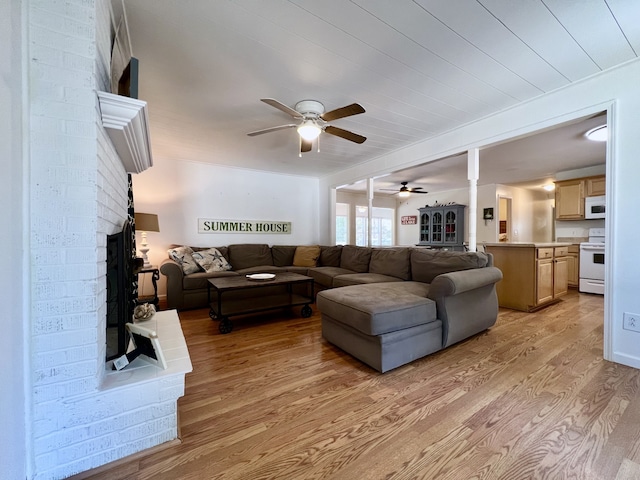 living room featuring a fireplace, ceiling fan, and light hardwood / wood-style floors