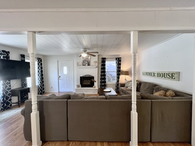 living room with a fireplace, ornamental molding, wood-type flooring, and ceiling fan