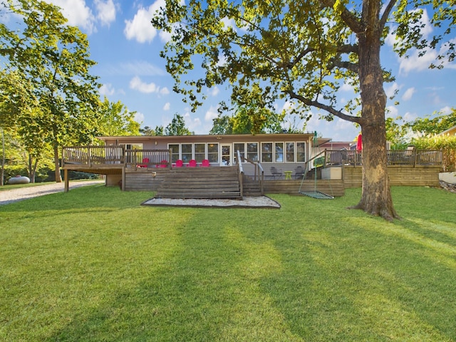 back of property with a wooden deck, a lawn, and a sunroom