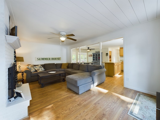 living room with light hardwood / wood-style floors, ceiling fan, and a fireplace