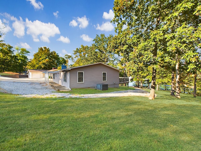 back of house featuring a lawn, a garage, and central AC