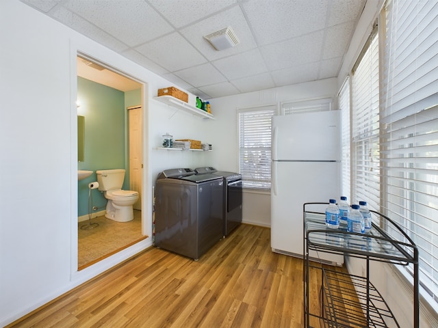 laundry area with washing machine and clothes dryer and light wood-type flooring