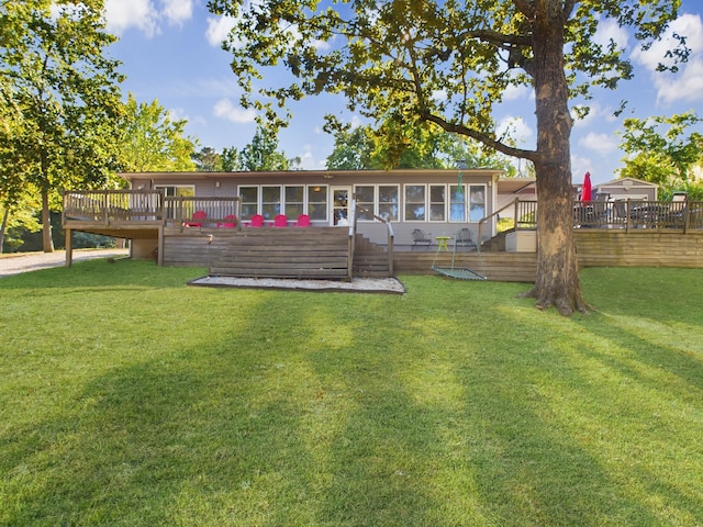 back of house featuring a wooden deck, a yard, and a sunroom