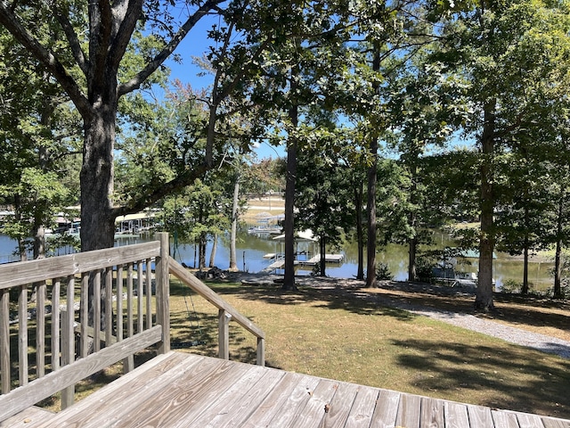 wooden terrace with a water view, a yard, and a dock