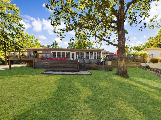 back of property with a sunroom, a yard, and a wooden deck